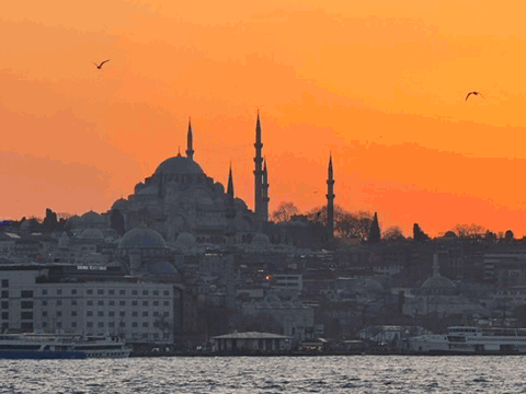 Istanbul skyline and mosque minarets at orange sunset across the water